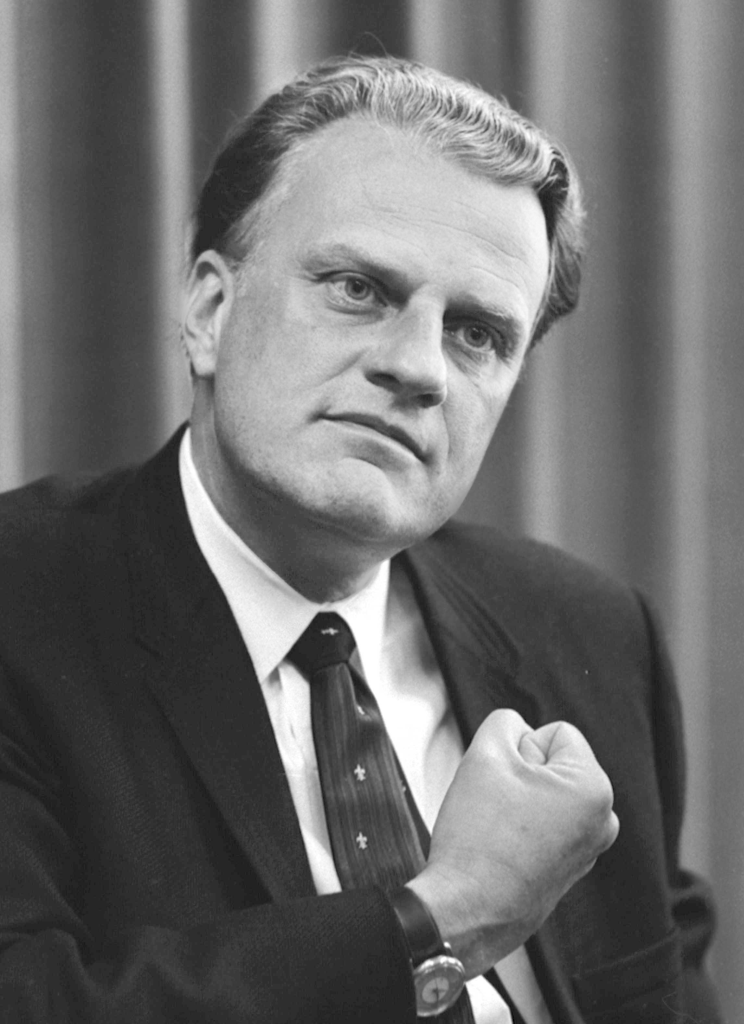 Black and white portrait of a man in a suit with a clenched fist, looking serious and thoughtful.
